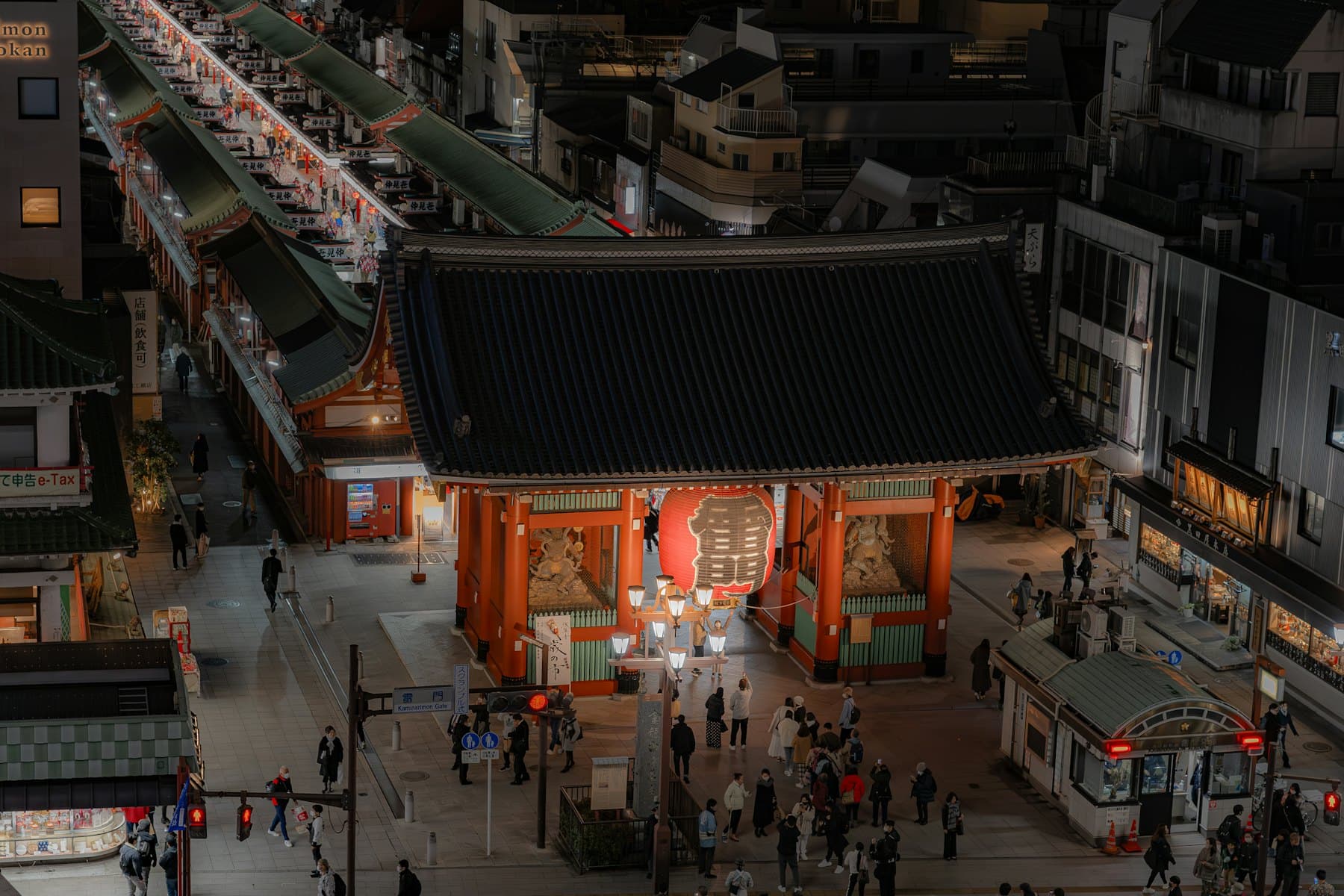 An illuminated temple gate above a busy Tokyo street after dark
